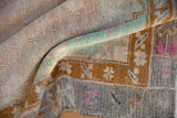 Softly worn pile of a distressed Kars carpet, showing mint green, bronze, and pink details.