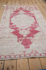 Distressed pale cochineal red patterns and abrashed ivory field on a vintage Oushak rug.