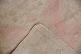Distressed Oushak runner's pink and beige pile, showing mostly even wear and exposed foundation.