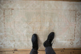 Black boots on a vintage distressed Oushak rug, revealing its faded ivory and blush pile.