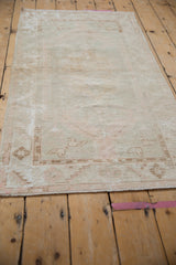 Distressed vintage Oushak rug with subtle geometric border in ivory, beige, and blush tones.