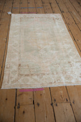 Distressed Oushak rug fringe with worn geometric patterns in ivory and blush.