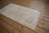 Softly faded vintage Oushak rug, showing subtle geometric motifs in pale beige and blush.
