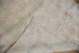 Vintage distressed Oushak rug corner with worn ivory and beige pile exposing its foundation and selvage.