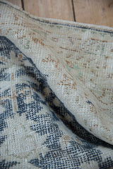 Distressed texture of vintage Sparta rug, with worn dusty navy, ivory, and sand tones.
