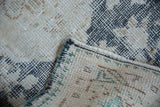 Distressed vintage Sparta rug's exposed foundation, even pile wear, and green-bound side cord.
