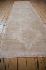 Angled view of a distressed Oushak runner showing its faint central medallion column.