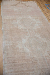 Angled view of a vintage Oushak runner showing its distressed texture and neutral beige palette.