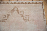 The coffee bronze chevron border and worn, low-pile texture of a vintage distressed Oushak rug.
