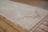 Angled view showing the mostly even wear and low pile of a distressed Turkish Oushak runner.