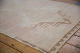 Angled close-up of a distressed Oushak runner's sand-colored chevron border and low, even pile.