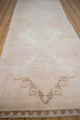 A long perspective view of the distressed vintage Oushak runner's repeating geometric pattern.