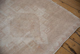 The soft, time-worn texture of a distressed Oushak runner's hand-knotted pile in neutral tones.