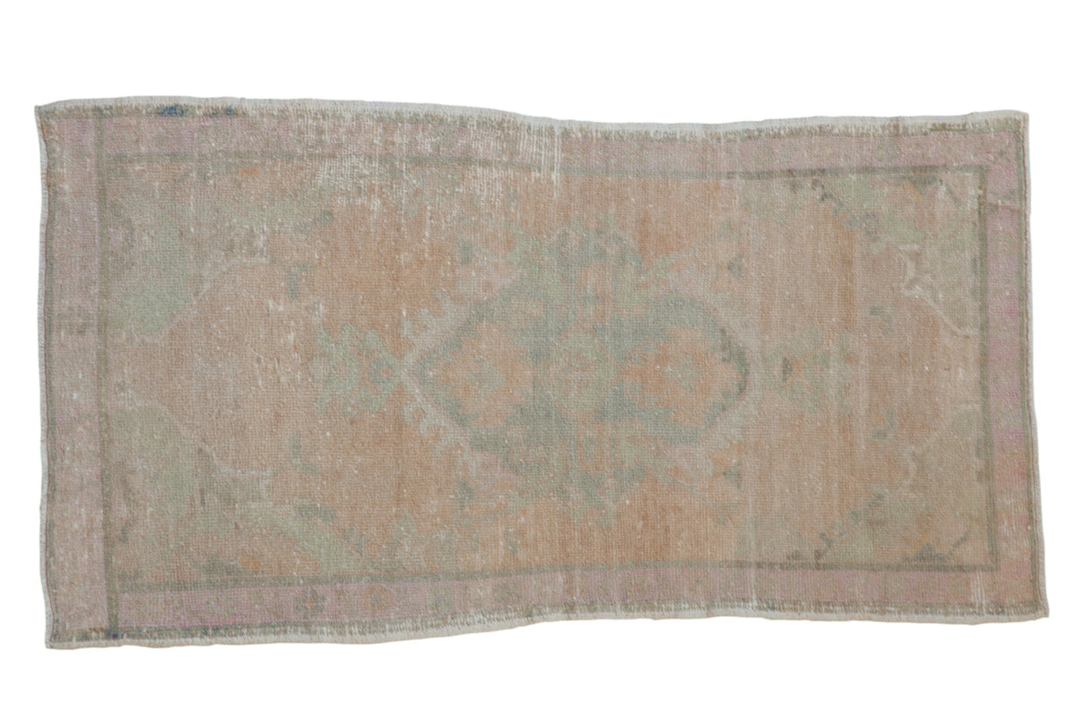 Vintage distressed Oushak rug with a faded floral medallion in soft tones of pale seafoam green and pink.