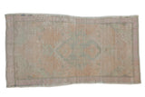 Vintage distressed Oushak rug with a faded floral medallion in soft tones of pale seafoam green and pink.