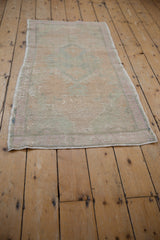 Full view of a small vintage Oushak rug, highlighting its characterful wear and uneven shape.