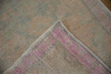 Corner of a vintage Turkish rug flipped to show its hand-knotted back with pink wefts.