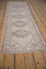 Distressed vintage Oushak runner featuring pale coffee geometric motifs and a rose border.