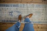 Distressed vintage Oushak runner, pale blue pattern on a worn ivory field.