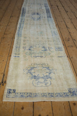 Distressed Oushak runner with pale blue germinating plant motif and visible foundation wear.