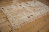 Distressed blush and brown Melas rug with faded patterned border and worn selvage.