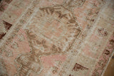 Worn low pile texture of a distressed Melas rug featuring blush, coffee brown, and ivory tones.