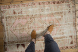Distressed vintage Melas rug with worn pile and faded pink, ivory patterns underfoot.