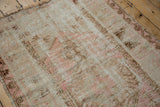 Distressed Melas rug corner with faded pink and brown patterns, showing secured blanket-stitched end.