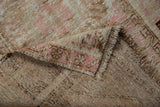Folded corner of vintage distressed Melas rug, revealing worn pile, foundation, and secured fringe.
