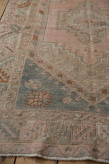 Melas rug detail with slate blue geometric serrated border and distressed blush pile.