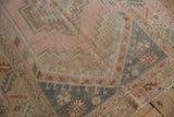 Distressed vintage Melas rug corner, with geometric patterns in blush, slate blue, copper.