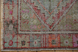 Hand knotted Oushak rug corner showing wear, exposed foundation, and geometric border pattern.