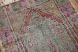 Distressed Oushak rug texture, revealing foundation and pops of red, pink, orange, green.