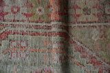 Close-up of vintage distressed Oushak rug showing worn knot heads and visible foundation.