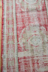 Textured vintage Oushak runner displaying worn cherry red pile, beige roundel, and red selvage.
