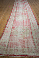 Distressed Oushak runner end with wear to foundation, cherry red, and faded beige.