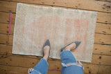 In-home view of a small vintage distressed rug showing its soft melon and ivory colors and texture.