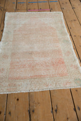 Angled view of the distressed Oushak rug, showing the worn texture and muted melon hues.