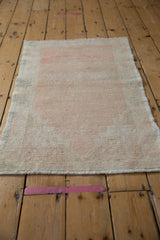 Angled view of a distressed vintage rug highlighting its soft, worn low pile and texture.