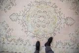 Distressed Oushak carpet, even wear on pale pink and seafoam green floral medallion.