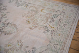 Distressed vintage Oushak carpet with faded pale pink and seafoam green floral patterns.