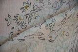 Distressed vintage Oushak carpet pile, showcasing faded pale pink and seafoam green florals.