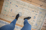 Distressed Oushak runner showing visible foundation, faded ivory, cobalt blue, and olive motifs.