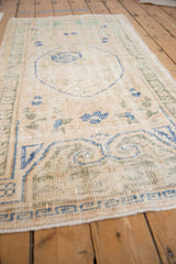 Distressed Oushak runner, worn ivory pile, visible knot heads, faded blue, green patterns.