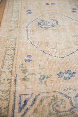 Distressed Oushak rug texture, showing faded ivory, cobalt blue, and olive green patterns.