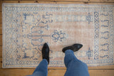 Distressed vintage Oushak rug with prayer motif in soft beige, ivory, and denim blue.