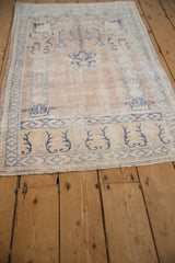 Faded blue and ivory geometric border with soft fringe on a distressed Oushak rug.