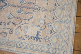 Artfully distressed Oushak rug, showing worn pile with faded beige, ivory, and blue patterns.