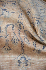 Close-up of distressed Oushak rug showing worn pile texture, beige and blue motifs.