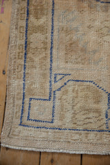 Distressed vintage Oushak rug corner, cobalt blue running serpent border, worn pile texture.